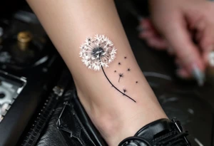 Dandelion puff rendered in soft white over pale gray shading, floating into barely-there seed trails on the ankle. tattoo idea