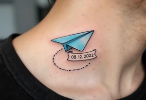 A cartoon-style paper airplane in soft grey and baby blue, trailing a banner with the birthdate 08. 12. 2022. tattoo idea