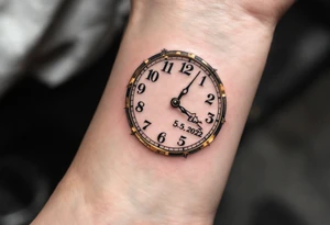 Delicate golden clock hands frozen at 9:17, with "Ela" and 3.5.2022 in fine black ink. tattoo idea