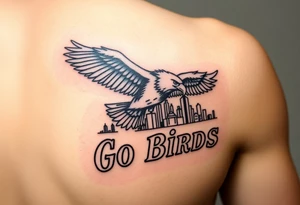 Tattoo On upper bicep 
Philadelphia Eagle classic bird flying over Philadelphia city skyline with the words Go Birds in bubble letters under it tattoo idea