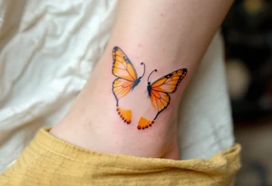 Bright yellow and pastel orange footprints of Tereza, gently paired with butterfly wings to capture her playful and free nature. tattoo idea