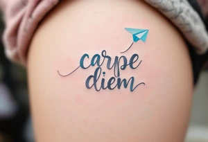 Flowing script in ink-wash gray "carpe diem", with a paper plane in pale blue flying above the phrase. tattoo idea