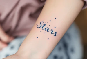 A quote in icy blue ink crosses the wrist with a constellation pattern forming the final word: Stars. tattoo idea
