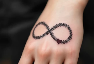 A lace-textured infinity outline in dark gray, with a soft burgundy heart sewn into the design. tattoo idea
