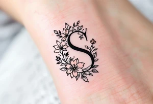 A minimalist black "S" outlined with fine-line flowers in soft pastel tones on finger. tattoo idea