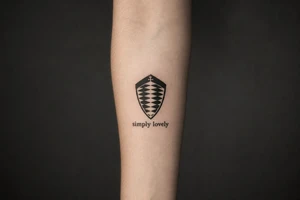Koenigsegg ghost logo and below written "simply lovely" tattoo idea