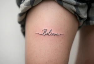 A delicate "Believe" in silver, intertwined with tiny feathers in soft white, symbolizing freedom and trust in the journey. tattoo idea