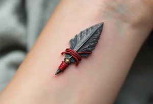 A hand-carved flint arrowhead in gray with red cord wrapping, symbolizing strength and survival tattoo idea