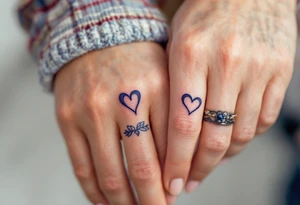 Matching tiny navy-blue heart tattoos on ring fingers of each partner tattoo idea
