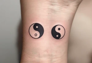 A yin-yang symbol split between two tattoos: the first half in black and white on one wrist, and the second complementary half in the same colors on the other wrist. tattoo idea