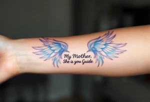 A pair of angel wings in light blue and lavender with “My Mother, She Is My Guide” between them. tattoo idea