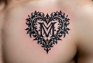 A black and grey ornamental heart with a bold Gothic-style letter "M", surrounded by subtle shading and filigree details. tattoo idea