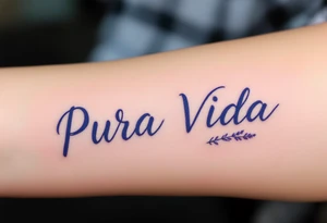 Simple cursive “Pura Vida” inked in navy blue with a small lavender sprig underlining the text. tattoo idea