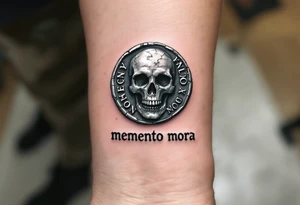 A Roman coin with a skull embossed in silver, the inscription "memento mori" in rough gray Latin lettering beneath it. tattoo idea