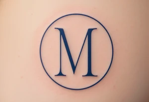 An elegant serif "M" in midnight blue, placed within a fine circular frame. tattoo idea