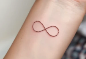 A thin, minimalist infinity outline in rose gold, with tiny white sparkles accenting the curves. tattoo idea