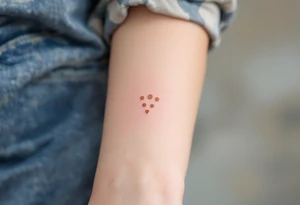 Three copper-toned dots forming an inverted triangle near the base of the thumb, signifying feminine energy and creativity. tattoo idea