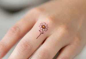 A band around finger with a single engraved daisy tattoo idea