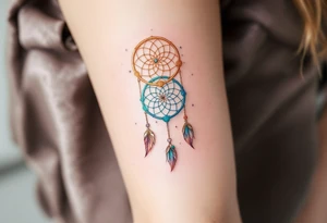 Three delicate dreamcatchers, each woven in a different hue—turquoise, gold, and silver—with small charms representing each person. tattoo idea