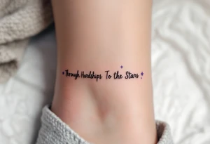 A simple black-ink tattoo wraps “Through Hardships To the Stars” around the ankle, with each word nestled between tiny violet stars. S tattoo idea