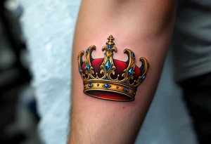 A regal gold crown tattoo adorned with deep red velvet lining, shimmering sapphire-blue gemstones, and subtle black shadowing underneath to give it a bold, three-dimensional look. tattoo idea