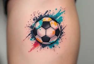 A small behind-the-ear soccer ball tattoo in black with a splash of teal paint. tattoo idea