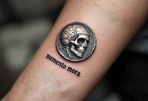 A Roman coin with a skull embossed in silver, the inscription "memento mori" in rough gray Latin lettering beneath it. tattoo idea