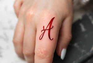 A script "A" formed by a red ribbon wrapping in the shape of the letter on one finger. tattoo idea