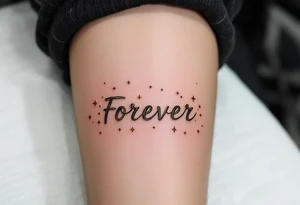 "Forever" etched in gold metallic ink across the spine, surrounded by tiny celestial stars. tattoo idea