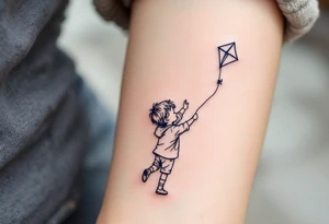 A line-art drawing of a child flying a kite, with the kite string forming the son’s name in dark navy ink. tattoo idea