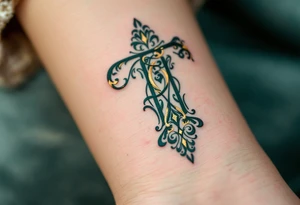 An ornate Victorian-style "T" in deep emerald green with gold leaf filigree. tattoo idea