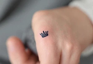 Tiny finger tattoos with black ink crown icons—spiky for king, rounded for queen. tattoo idea