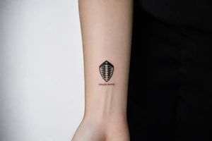 Koenigsegg ghost logo and below written "simply lovely" tattoo idea