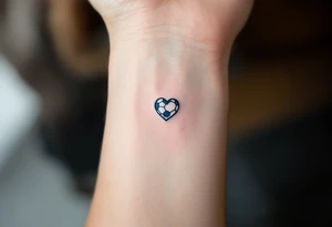 A minimalist black outline of a soccer ball with a single blue heart at its center. tattoo idea