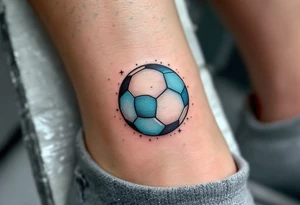 A small ankle tattoo of a pastel blue soccer ball with sparkles around it for a playful look. tattoo idea