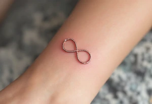 A thin, minimalist infinity outline in rose gold, with tiny white sparkles accenting the curves. tattoo idea