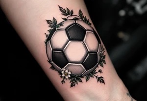 A shaded black soccer ball with green vines and small white flowers wrapping it. tattoo idea