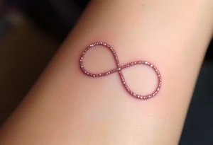 A thin, minimalist infinity outline in rose gold, with tiny white sparkles accenting the curves. tattoo idea