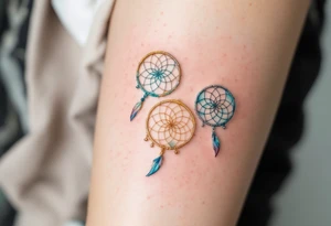 Three delicate dreamcatchers, each woven in a different hue—turquoise, gold, and silver—with small charms representing each person. tattoo idea