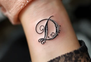 Elegant Script D – A flowing cursive letter D in black ink with delicate silver filigree details wrapping around the curves. tattoo idea
