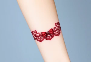 A deep red lace garter design, with a satin bow and subtle gemstone details for a sensual aesthetic tattoo idea