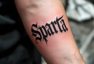 The word “SPARTA” written in Gothic script across the forearm, half in hockey red, half in football maroon. tattoo idea