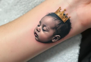 Profile portrait of a baby girl’s sleeping face with a tiny gold crown, with realistic detail. tattoo idea