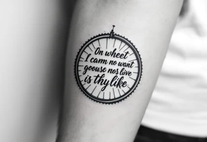 A motivational quote wrapped around a bike wheel, in elegant cursive script with subtle navy blue accents. tattoo idea