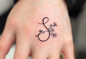 A minimalist black "S" outlined with fine-line flowers in soft pastel tones on finger. tattoo idea