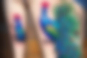 colourfull male peacock on thigh with feathers down to the ankle tattoo idea
