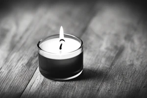 a single old burning candle sitting on a small wood table. The candle and the table are the only things in the room tattoo idea