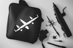 a minimal tattoo shows an airplane flying out of a suitcase to travel tattoo idea