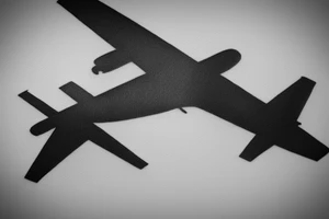 a minimal tattoo shows an airplane flying out of a suitcase to travel tattoo idea