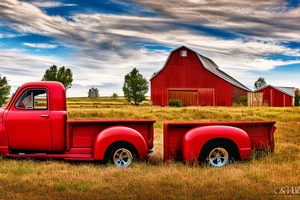 A rustic red and white '53 5-window GMC long bed pickup parked at an angle in front of a red barn with the setting sun in the background. The setting sun is shaped like a sunflower. tattoo idea